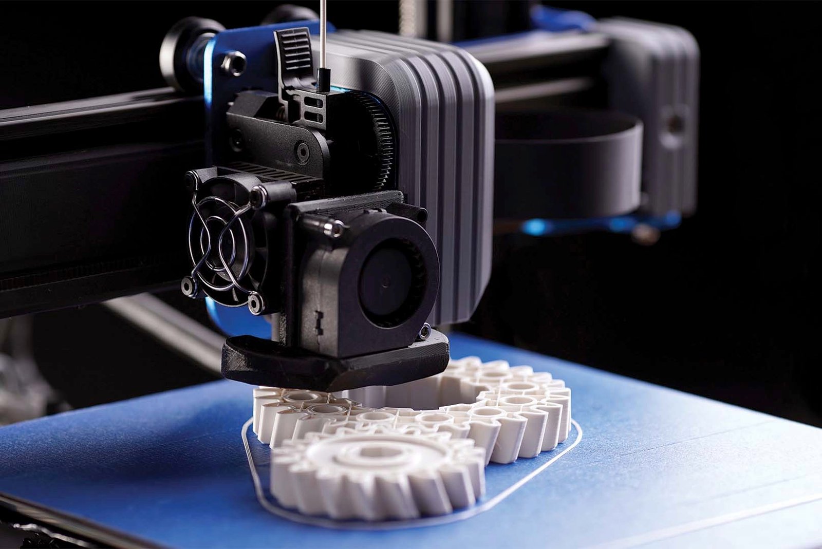 A 3D printer building a set of white plastic gears